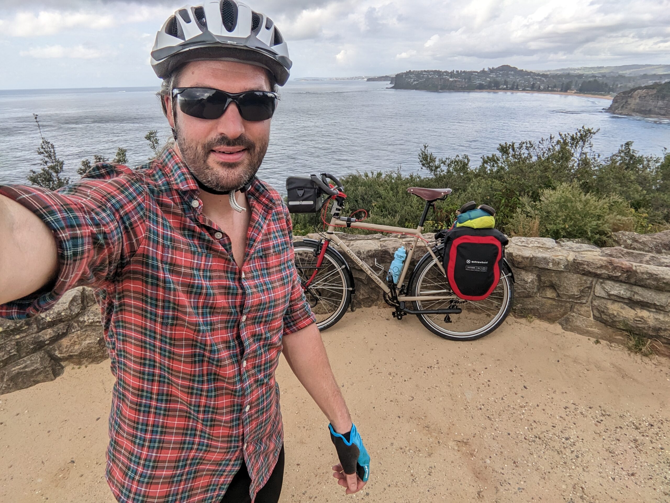 Selfie of adventure cyclist Tom Allen and his bike at Bilgoa Lookout with the the coast of New South Wales in the background.